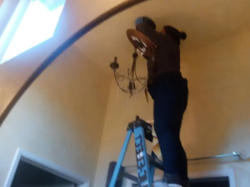 Electrician installing a chandelier in a Fort Mill residence